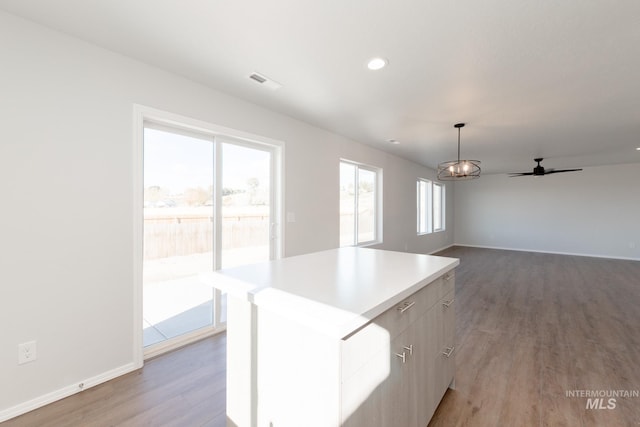 kitchen featuring light wood finished floors, a center island, baseboards, pendant lighting, and light countertops