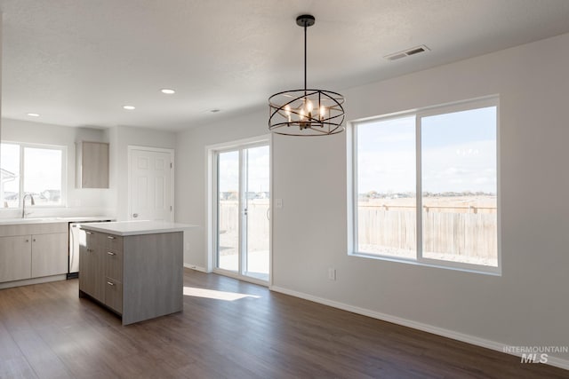 kitchen featuring baseboards, visible vents, a kitchen island, dark wood-style flooring, and a sink