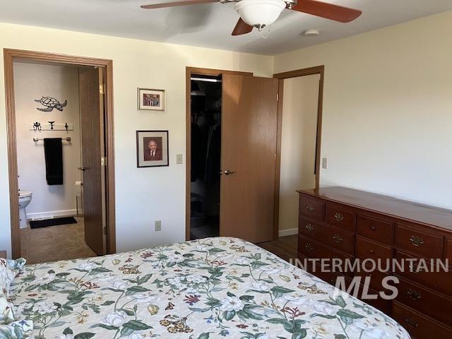 bedroom with ceiling fan, a closet, baseboards, and ensuite bath