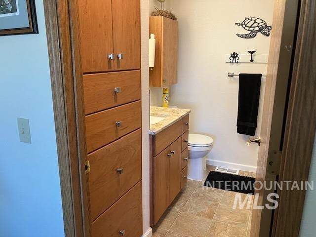 bathroom featuring vanity, baseboards, visible vents, tile patterned floors, and toilet