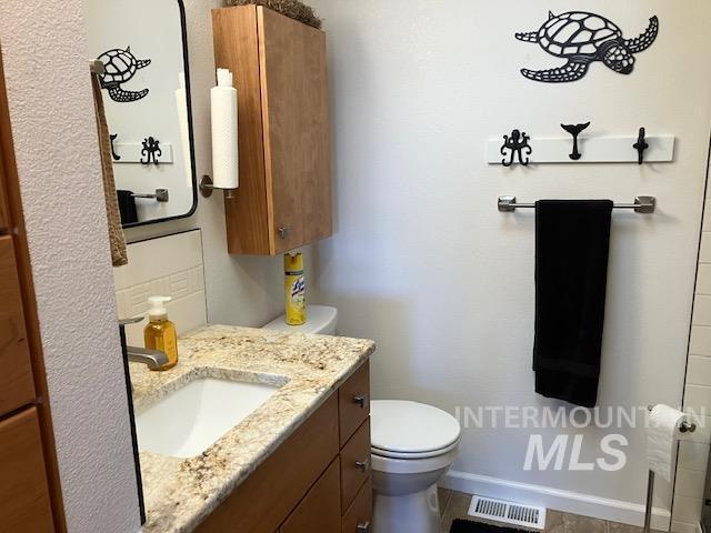 bathroom with visible vents, toilet, vanity, and baseboards