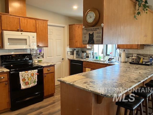 kitchen featuring black appliances, brown cabinetry, and a peninsula