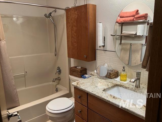 bathroom with decorative backsplash, toilet, vanity, and shower / bath combination with curtain