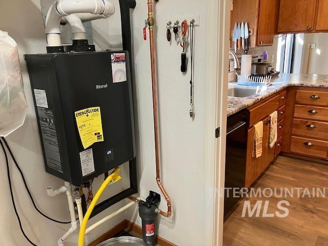 utility room with water heater and a sink