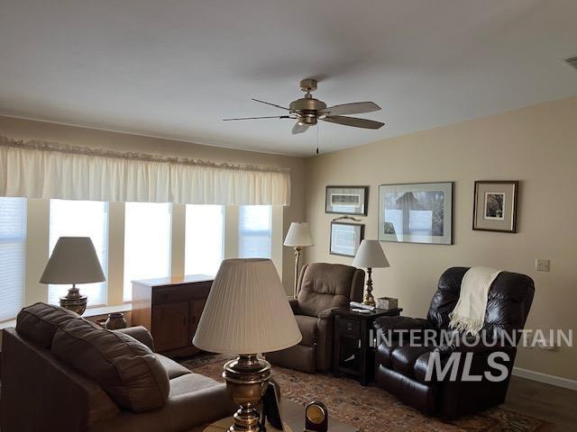 living room featuring baseboards, visible vents, a ceiling fan, and lofted ceiling