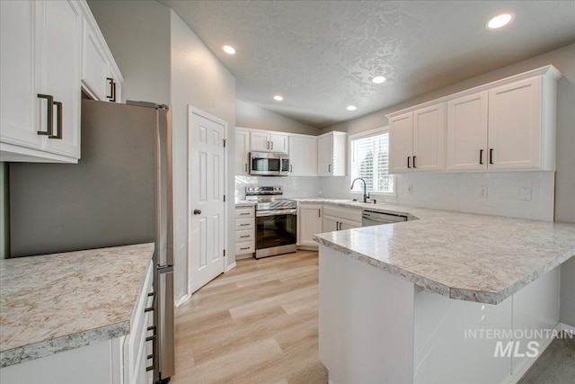 10683 W Capella St, Star, ID 83669 - kitchen with kitchen peninsula, white cabinetry, light hardwood / wood-style flooring, and appliances with stainless steel finishes