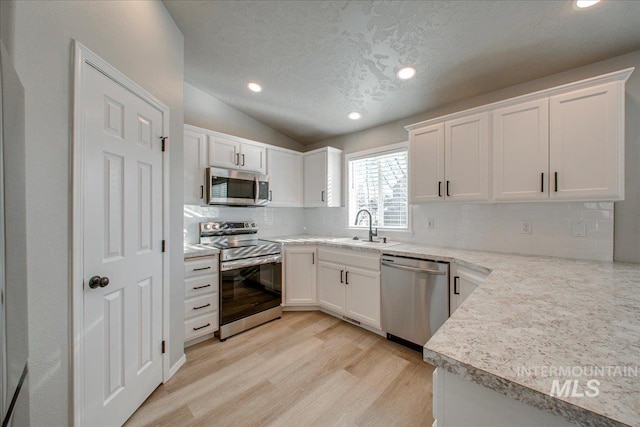 10683 W Capella St, Star, ID 83669 - kitchen with light hardwood / wood-style floors, white cabinets, sink, stainless steel appliances, and lofted ceiling