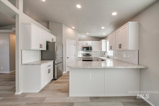 10683 W Capella St, Star, ID 83669 - kitchen with white cabinets, lofted ceiling, stainless steel appliances, kitchen peninsula, and light hardwood / wood-style flooring