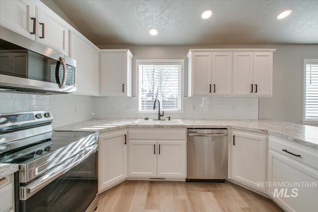 10683 W Capella St, Star, ID 83669 - kitchen featuring sink, white cabinets, light wood-type flooring, and appliances with stainless steel finishes