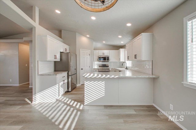 10683 W Capella St, Star, ID 83669 - kitchen with kitchen peninsula, appliances with stainless steel finishes, sink, white cabinetry, and light hardwood / wood-style floors