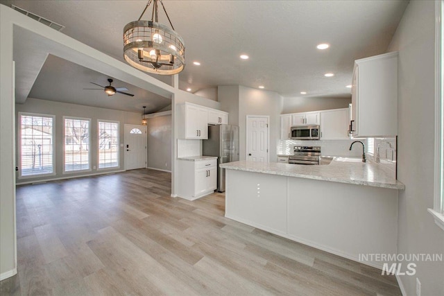 10683 W Capella St, Star, ID 83669 - kitchen featuring appliances with stainless steel finishes, tasteful backsplash, white cabinets, sink, and kitchen peninsula
