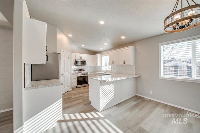 10683 W Capella St, Star, ID 83669 - kitchen featuring white cabinetry, stainless steel appliances, hanging light fixtures, kitchen peninsula, and vaulted ceiling
