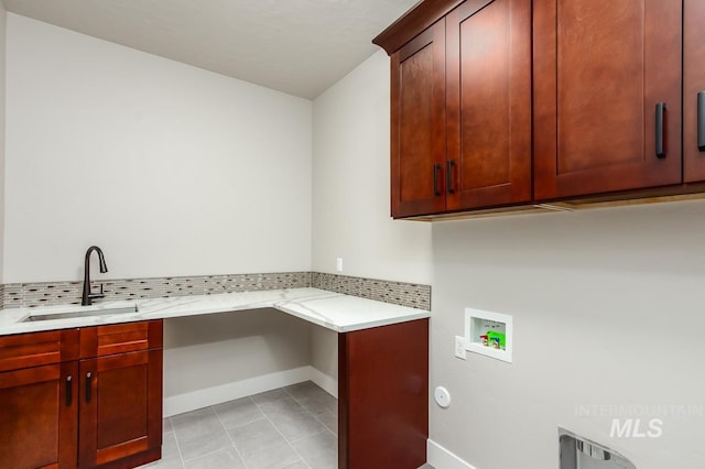 clothes washing area with hookup for a washing machine, light tile patterned floors, cabinets, and sink