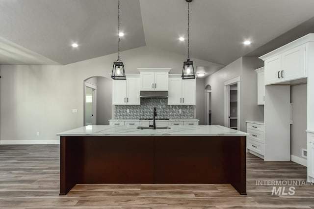 kitchen featuring decorative light fixtures, a kitchen island with sink, hardwood / wood-style flooring, white cabinetry, and lofted ceiling