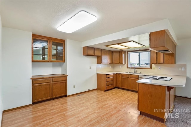 16476 Ustick Rd, Caldwell, ID 83607 - kitchen featuring brown cabinets, a peninsula, a sink, and light wood-style floors