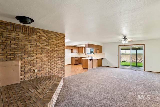 16476 Ustick Rd, Caldwell, ID 83607 - unfurnished living room with brick wall, ceiling fan, light carpet, and a textured ceiling