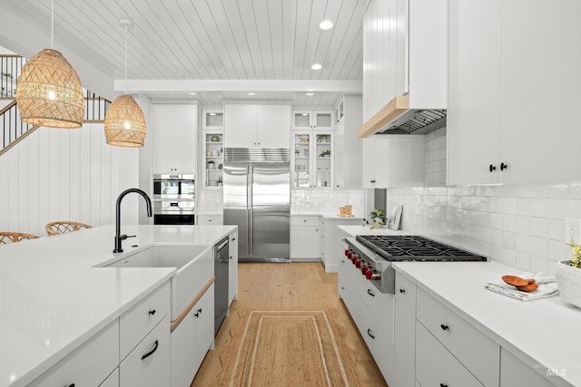 kitchen featuring light countertops, decorative backsplash, appliances with stainless steel finishes, hanging light fixtures, and white cabinetry