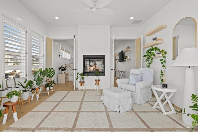 living area featuring wood finished floors, recessed lighting, visible vents, and a multi sided fireplace