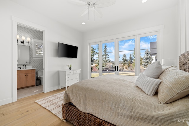 bedroom featuring ceiling fan with notable chandelier, recessed lighting, connected bathroom, light wood finished floors, and baseboards