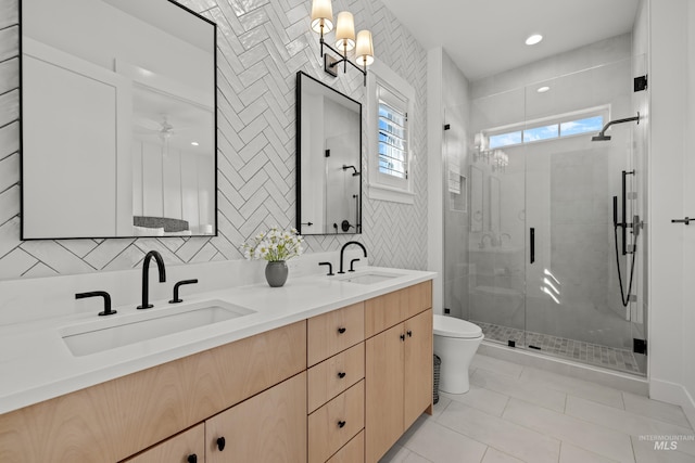 bathroom with a sink, toilet, double vanity, and a shower stall