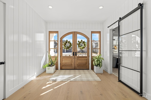 entryway featuring recessed lighting, light wood-style flooring, french doors, and a barn door