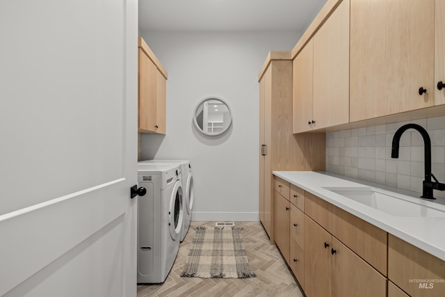 laundry area with washer and dryer, cabinet space, baseboards, and a sink