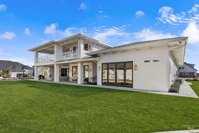 back of property featuring a patio, a balcony, central AC, stucco siding, and a lawn