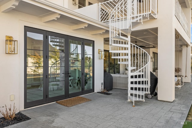 property entrance with a patio area, stucco siding, and french doors