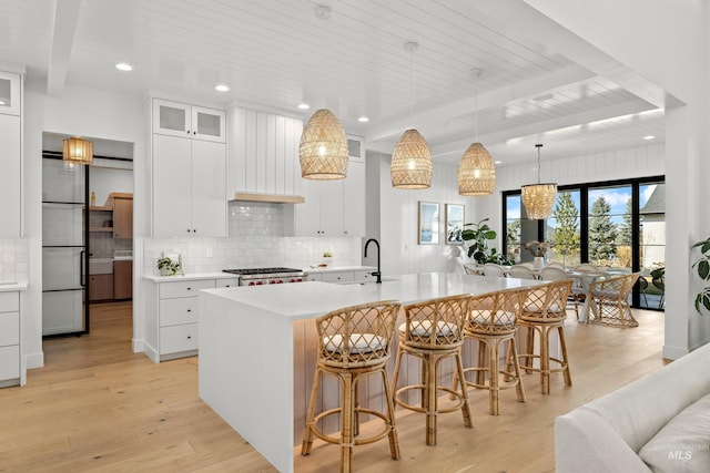 kitchen with light countertops, a breakfast bar area, light wood-type flooring, and backsplash