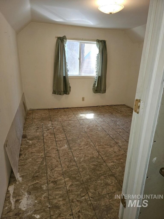 unfurnished room with vaulted ceiling