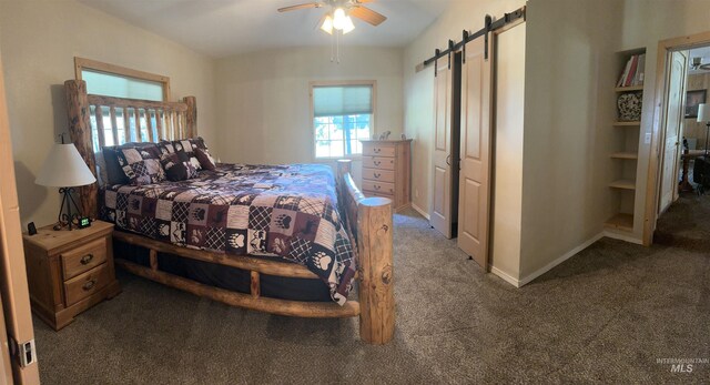 carpeted bedroom with a ceiling fan, baseboards, a barn door, and multiple windows