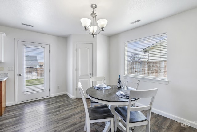dining area featuring dark wood-type flooring, a chandelier, and visible vents
