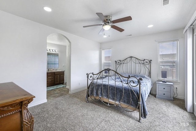 bedroom with baseboards, recessed lighting, arched walkways, and light colored carpet