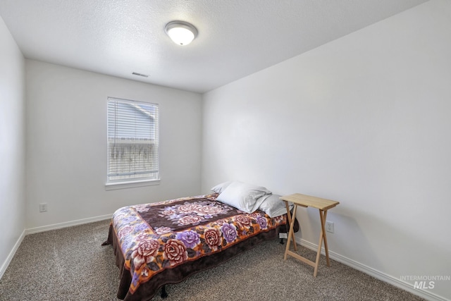 bedroom featuring visible vents, baseboards, a textured ceiling, and carpet floors