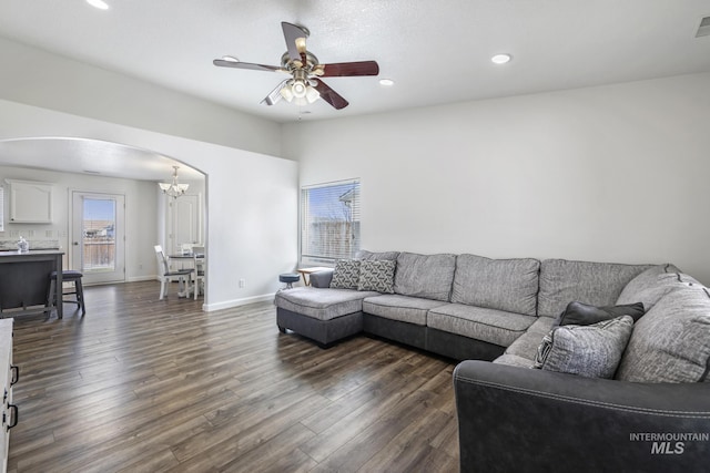 living area featuring baseboards, arched walkways, recessed lighting, ceiling fan with notable chandelier, and dark wood-type flooring