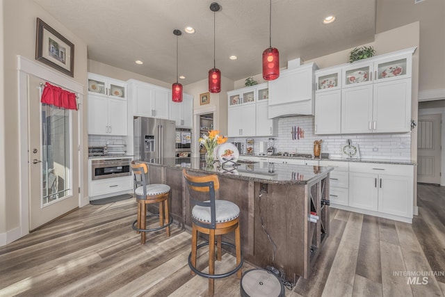 420 Poppy St, Fruitland, ID 83619 - kitchen with appliances with stainless steel finishes, wood finished floors, decorative backsplash, a center island, and a breakfast bar