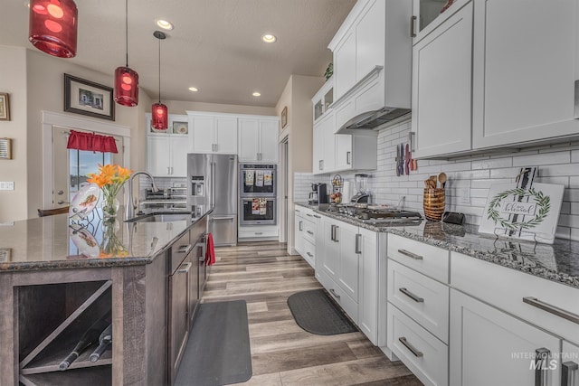 420 Poppy St, Fruitland, ID 83619 - kitchen with a sink, appliances with stainless steel finishes, premium range hood, light wood finished floors, and glass insert cabinets