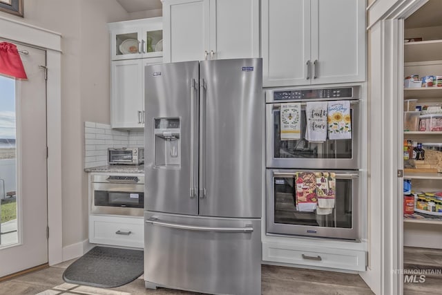 420 Poppy St, Fruitland, ID 83619 - kitchen featuring stainless steel appliances, white cabinetry, glass insert cabinets, backsplash, and wood finished floors