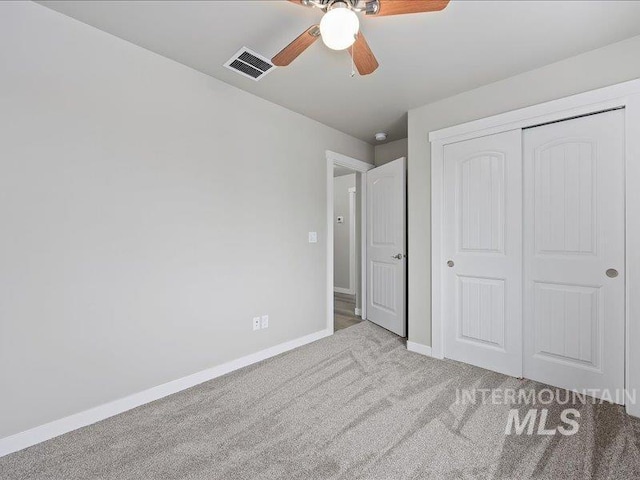 unfurnished bedroom featuring light colored carpet, a ceiling fan, baseboards, visible vents, and a closet