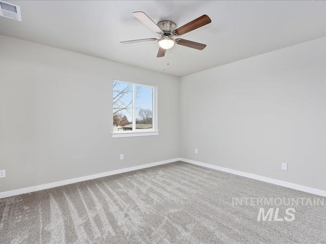 empty room featuring a ceiling fan, light colored carpet, visible vents, and baseboards