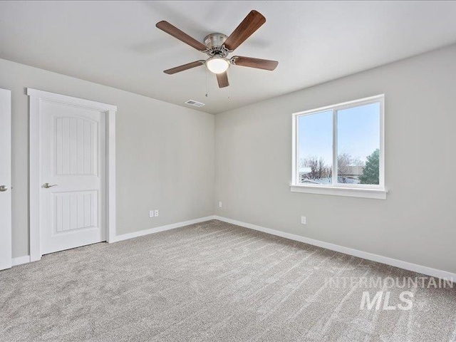 empty room with carpet floors, visible vents, ceiling fan, and baseboards