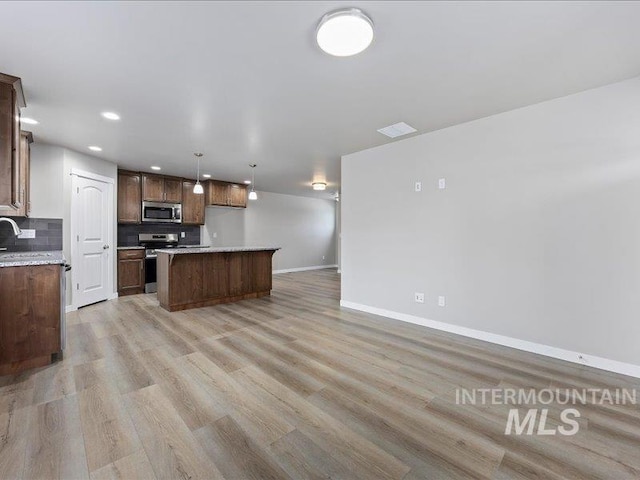 kitchen with a kitchen island, open floor plan, light countertops, appliances with stainless steel finishes, and hanging light fixtures