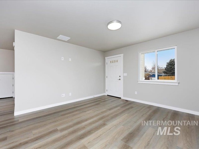 unfurnished room with baseboards, visible vents, and light wood finished floors