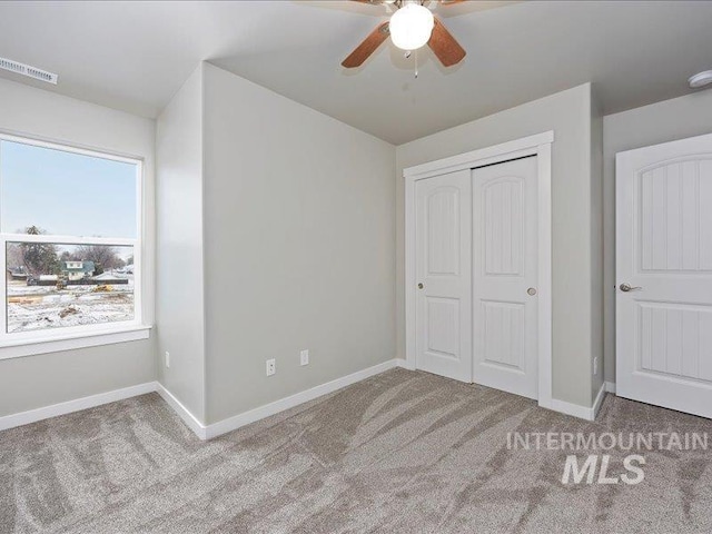 unfurnished bedroom featuring baseboards, visible vents, a closet, and light colored carpet