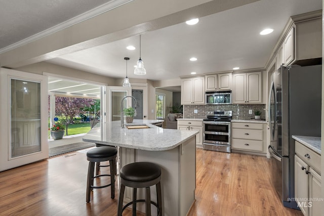 4545 N Columbine St, Boise, ID 83646 - kitchen featuring appliances with stainless steel finishes, a sink, tasteful backsplash, light wood finished floors, and a kitchen breakfast bar