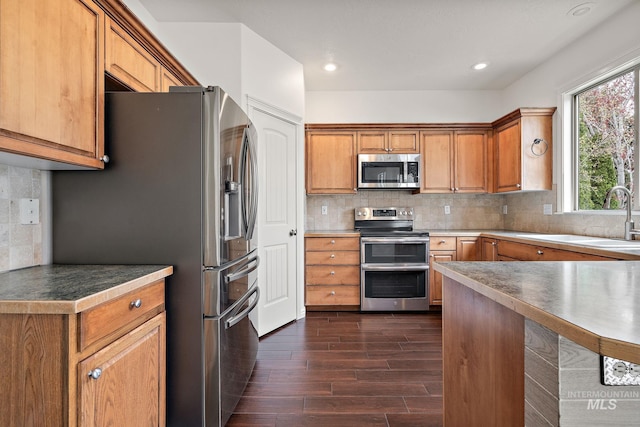 1452 E Pistioa Dr, Meridian, ID 83642 - kitchen featuring appliances with stainless steel finishes, dark wood-style floors, backsplash, brown cabinets, and recessed lighting