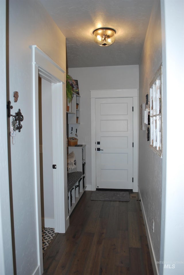 entryway featuring dark wood-style floors, baseboards, and a textured wall