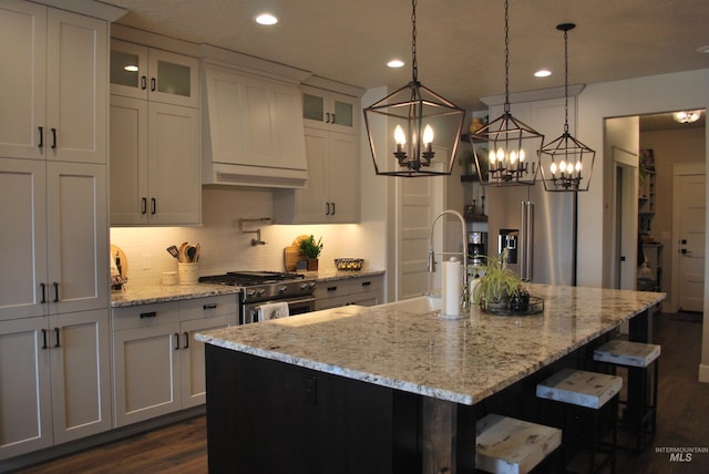 kitchen featuring custom range hood, a sink, premium appliances, tasteful backsplash, and dark wood-style flooring