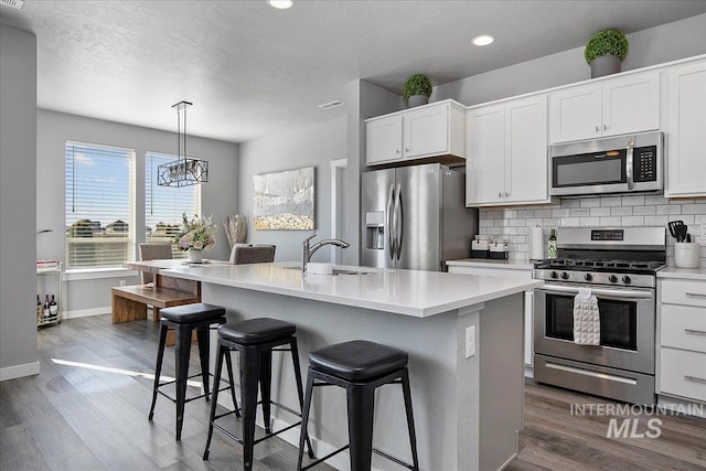 kitchen featuring appliances with stainless steel finishes, wood finished floors, and tasteful backsplash