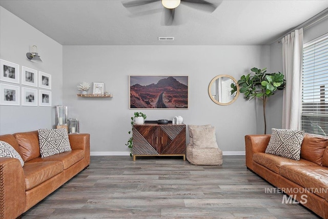 living room with ceiling fan, wood finished floors, visible vents, and baseboards